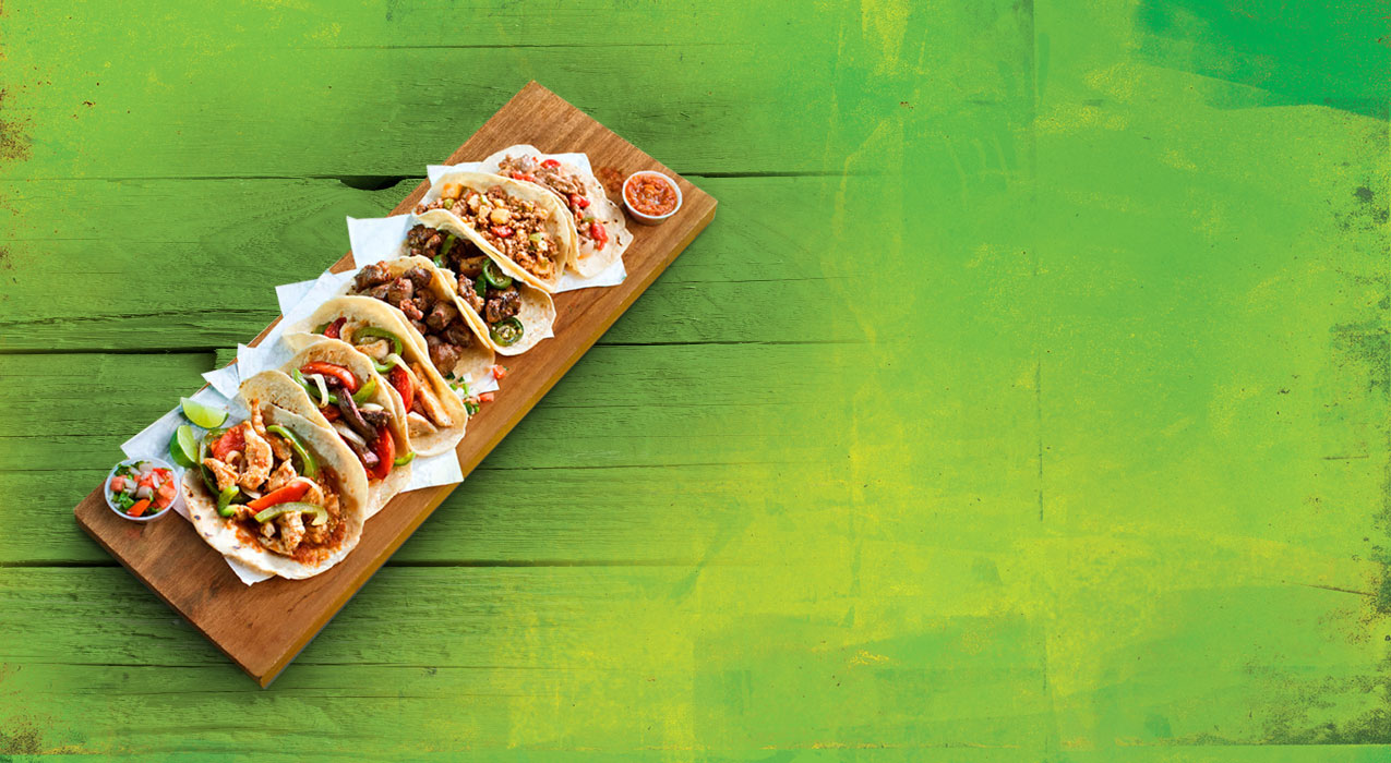 Tacos on wooden board with green background