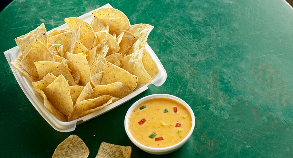Corn Chips with Nacho Queso on a Green Table